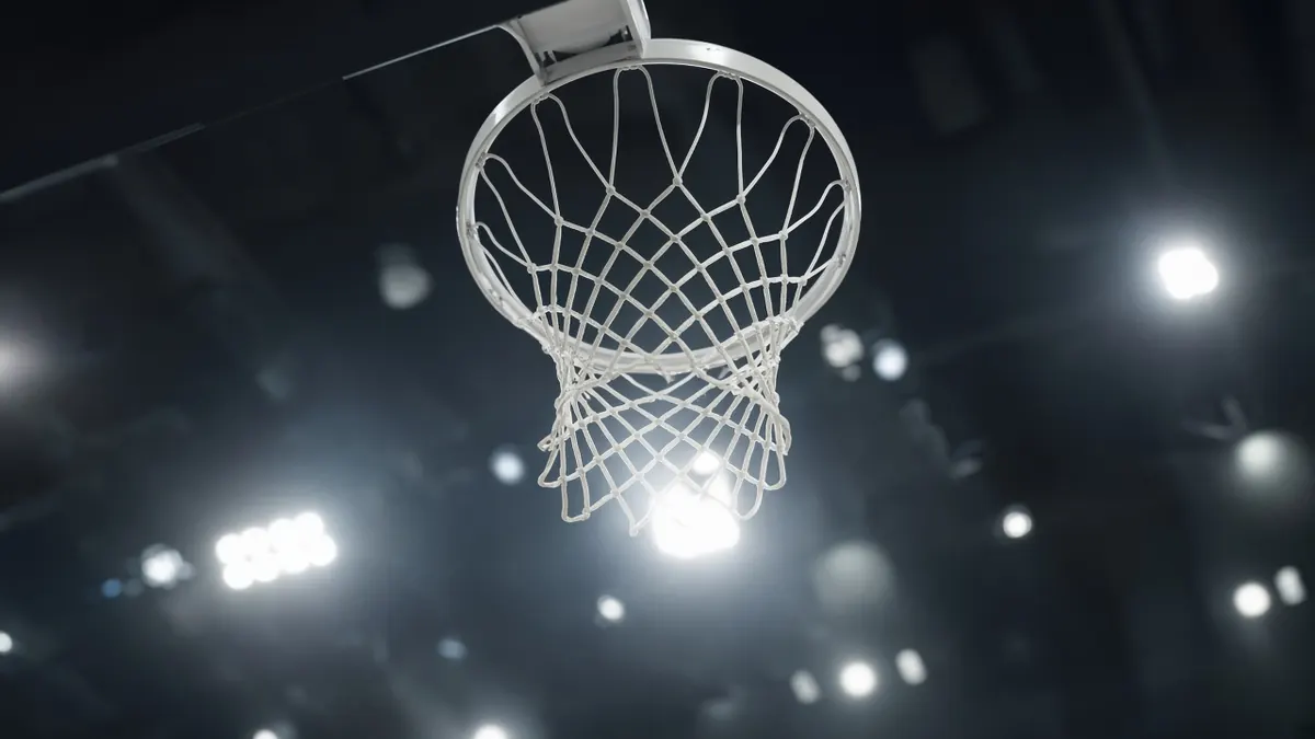 Illustration of a basketball hoop and net seen from below against bright arena lights