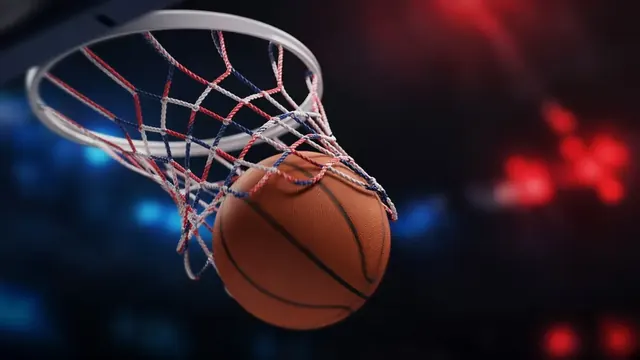 A basketball game in a packed arena with blue lights, a player rising for a jump shot as a blurred crowd watches